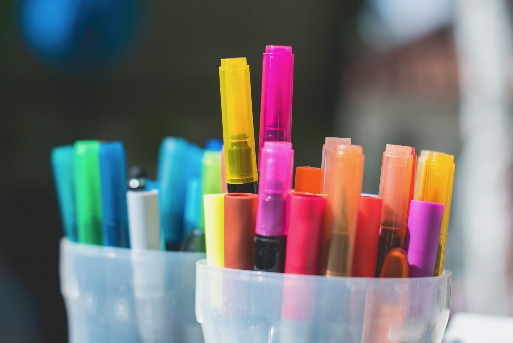 Zwei Becher voller bunter Stifte als Symbol für kreative Biografiearbeit und Teile-Arbeit im Workshop